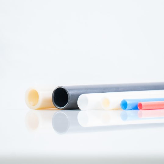 Beispielbild Produktion in der Extrusion: bunte Kunststoffrohre von Friedenstab liegen auf einer weißen Fläche